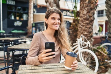 Sticker - Young blonde woman using smartphone drinking coffee at coffee shop terrace