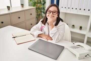 Down syndrome woman wearing doctor uniform smiling confident at clinic