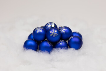 Wall Mural - Collection of blue holiday ornaments with glittered snowflakes on front displayed on a snowy background