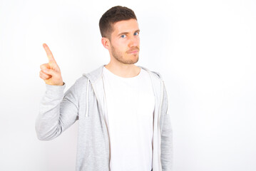 No sign gesture. Closeup portrait unhappy young caucasian man wearing casual clothes over white background  raising fore finger up saying no. Negative emotions facial expressions, feelings.