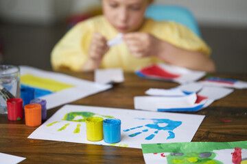 Sad child girl draws a picture of the war in Ukraine. Bright drawing with colors of the State flag of Ukraine, yellow and blue. Stop the war, save the world