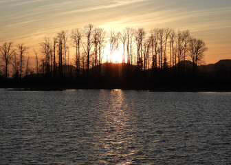 Wall Mural - Late autumn sunset sparkling in the wrinkled lake