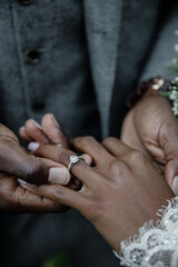 Wall Mural - African American Groom puts a wedding ring on his bride's finger during the wedding ceremony Marriage concept Groom in grey suit puts Wedding Ring on Bride's finger Exchange of rings	