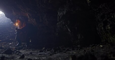 Wall Mural - medieval monk, or beggar, with a beard sits in a dark cave with a candle in his hands and waits. cin