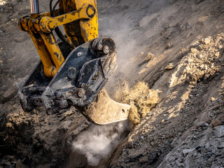 Excavator ripper attachment ripping frozen soils on construction site