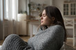 © fizkes - Young woman covered in warm knitted plaid sits on sofa at home suffers from low temperature in living room, shivers, having flu symptoms feeling unwell. Heating problem, catch cold, discomfort concept
