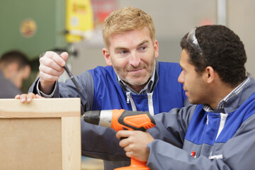 repairmen working with power drill in workshop