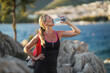 © milanmarkovic78 - Woman Runner Is Drinking Water And Taking A Break After Jogging Near To Sea