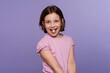 Cute Child girl with big round white pill on tongue in mouth on lilac background. Taking medicine, vitamin supplements, treatment concept. Complete multivitamin. Healthcare and health care