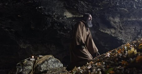 Wall Mural - hermit man with robe in the entrance of a old cave in front of a valley