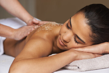 Massaging away all the worries and stress. Shot of a young woman enjoying a back massage at a spa.