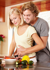 Sticker - Embracing their love of food. A happy young couple cooking in the kitchen.