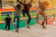 Group of young skaters flying over a ramp in a skate park