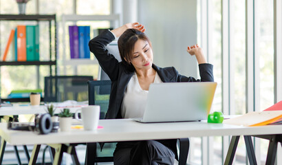 Asian young tired exhausted lazy sleepy female businesswoman secretary employee staff in formal suit sitting take break relaxing resting from working stretching arms relief stress in company office