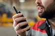 © pressmaster - Hand of bearded worker of plant speaking in portable radio transceiver while giving instructions to subordinates in warehouse