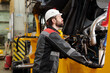 © pressmaster - Young technician or repairman in hardhat and uniform standing by industrial machine while checking its engine system