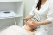 © Наталья Канищева - Facial massage. The cosmetologist makes a facial massage for an attractive brunette woman. Professional care of the skin and muscles of the face. rejuvenating beauty treatments.