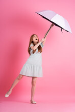 Young Asian Woman Holding Umbrella On Pink Background
