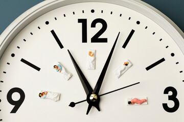 miniature people sleeping on the clock