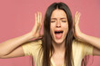 Closeup portrait stressed frustrated woman screaming having temper tantrum isolated on pink background. Negative human emotion facial expression reaction attitude