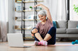 © Syda Productions - sport, fitness and healthy lifestyle concept - smiling senior woman exercising with laptop computer on mat at home