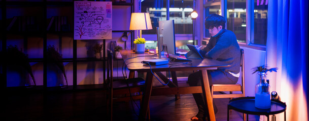 asian male creative designer working late night at home studio,home studio of sound engineer or programer with freelancer young adult asia casual cloth working overtime at night with urban city bokeh