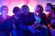 © Seventyfour - Portrait of young African American man with diverse group of friends at party in neon lights