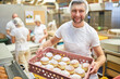 © Robert Kneschke - Bäcker Lehrling trägt frische Pfannkuchen in der Bäckerei