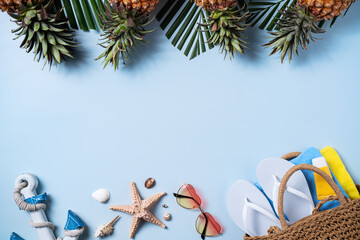 Wall Mural - Summer fruit background design concept. Beach with shells, hat, pineapple and palm leaves on blue background.