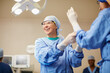 © Daniel L/peopleimages.com - Protecting themselves against germs. Shot of surgeons putting on surgical gloves in preparation for a surgery.