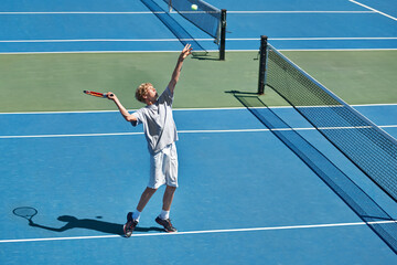 Hell be a start one day. Shot of a young boy playing tennis on a sunny day.