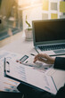 © ArLawKa - Businessman holding pen to analyze financial markets Young man works in office using laptop while analyzing document in hand. Financial concept graphs and calculators with vertical images.