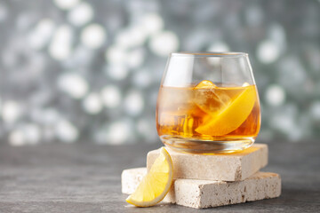 Wall Mural - Glass of whiskey with lemon and ice on stone background.