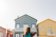 © Eva - back view of backpacker woman in front of colorful houses.promenade of Costa Nova, Aveiro, Portugal