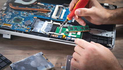 Wall Mural - Technician repairing laptop with a screwdriver.