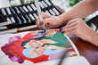 © Yakobchuk Olena - Female artist sitting at table wand making some illustrations with color markets at home