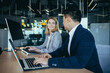 © Liubomir - happy coworkers discuss project strategy by looking and pointing at laptop pc computer monitor screen. multiethnic business team in the office. confident mature asian man explaining young female