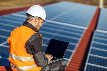 Wall Mural - A worker testing solar panels on the laptop on roof.