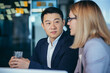 © Liubomir - Two employees are having fun. Asian man and blonde woman taking a break, colleagues working together in a modern office