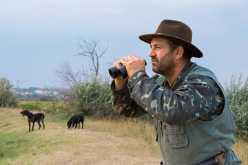 Wall Mural - Hunter man in camouflage with a gun during the hunt in search of wild birds or game. Autumn hunting season.