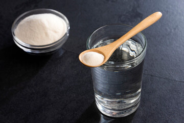 Canvas Print - Powdered collagen protein in the spoon. Glass of water