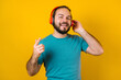 © Marcos - portrait of hispanic young bearded man with headphones, dancing and listening music on yellow background in Mexico Latin America