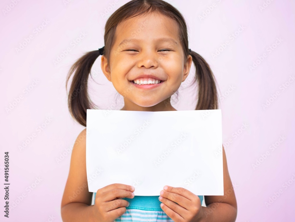 A little girl smiling holding a blank white paper sign. Happy kids ...