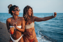 Friends Enjoying Vacation Together And Taking Selfie On The Beach Using Smartphone