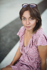 Portrait of a young beautiful brunette posing on the street in a soft pink sundress