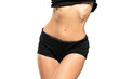 © vladimirfloyd - Close up shot of unrecognizable fit woman in black shorts isolated on white background. Torso of slim attractive female with flat belly.