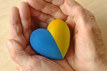 Woman hands holding heart in Ukrainian flag colors - Concept of stop war and pray for Ukraine