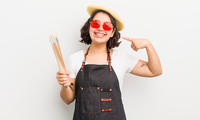 Wall Mural - pretty hispanic girl smiling confidently pointing to own broad smile. art student concept