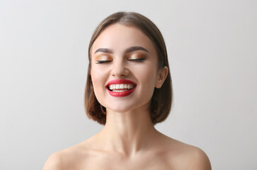 Canvas Print - Happy woman with closed eyes and red lipstick on light background