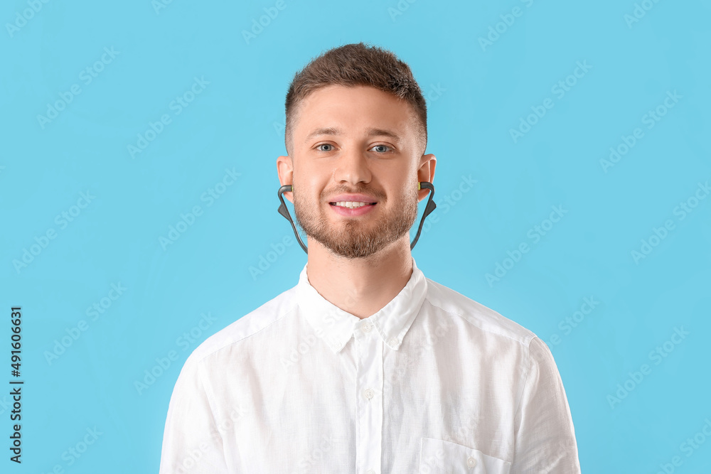 Young man with ear plugs on blue background